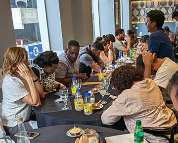 Latin_America_Conference_2025_Project_155_Prayer_Zoomed Group seated at tables bows their heads in prayer