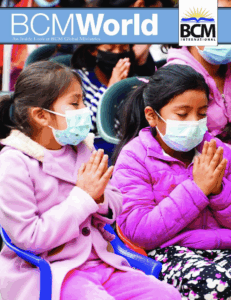 two children praying with masks on